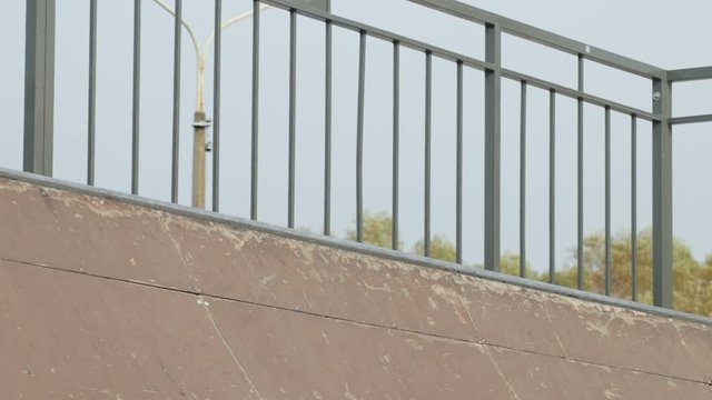 Male skater takes a skateboard from top of ramp and go, close-up, slowmotion