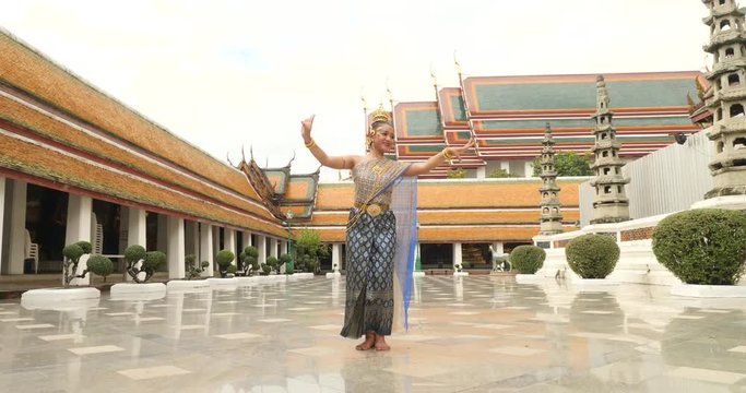 beautiful asian woman in thai traditional dress dancing traditional thai dance in Thai buddhist temple in bangkok wat suthat. outdoor next to temple