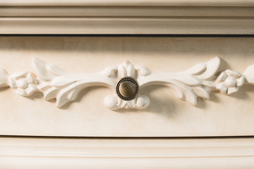 Close-up element of the drawer in the cabinet with a metal handle and wooden patterns. Detail of new furniture