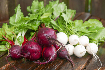 Red beets and white turnips with greens  on an old wooden table