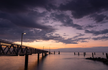 Fototapeta na wymiar Stormy skies and beach jetty at sunset