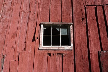 Obraz na płótnie Canvas Pocono Mountains, Pennsylvania, USA: The window of an abandoned red barn with broken glass and peeling red paint.