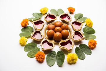 Happy Dussehra / Vijayadashami / Ayudh Puja greeting card using apta/Bauhinia racemosa/Bidi leaf and indian sweet Rasgulla or Gulab Jamun for Navaratri along with Diya/oil lamp