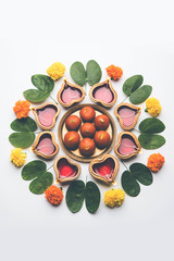 Happy Dussehra / Vijayadashami / Ayudh Puja greeting card using apta/Bauhinia racemosa/Bidi leaf and indian sweet Rasgulla or Gulab Jamun for Navaratri along with Diya/oil lamp