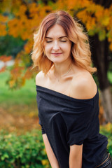 Charming woman in a black dress in the autumn park