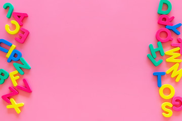 Alphabet for kids concept. English letters in disorder on pink background top view copy space