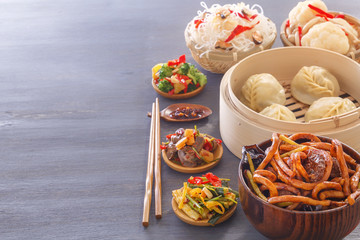 Dishes of Chinese cuisine in assortment. Steam dumplings, noodles, salads, vegetables, mushrooms, seafood. Copy space