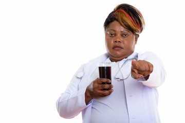 Studio shot of fat black African woman doctor holding glass of s