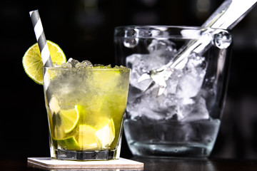 Caipirinha cocktail alongside with bucket full of ice.