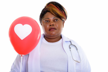 Thoughtful fat black African woman doctor holding red balloon wi