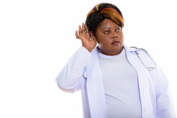 Studio shot of fat black African woman doctor listening while th