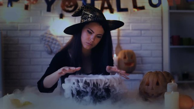 Beautiful witch performing mysterious magic ritual, cooking potion in cauldron