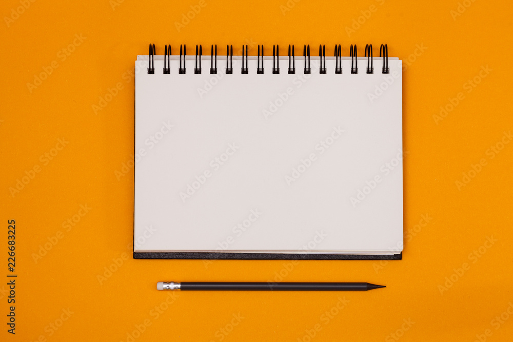 Fototapete blank spiral notebook and pencil on orange background. top view with copy space for input the text.