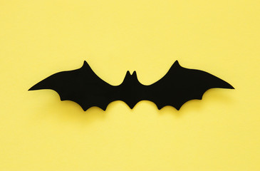 Halloween holiday concept. Black bats over yellow background. Top view, flat lay.
