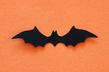 Halloween holiday concept. Black bats over orange background. Top view, flat lay.