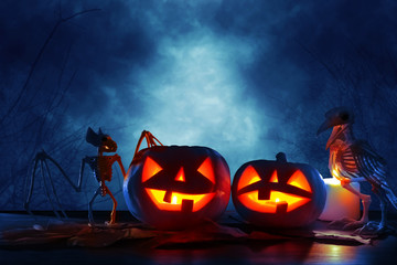 Halloween holiday concept. Pumpkins over wooden table at night scary, haunted and misty forest.