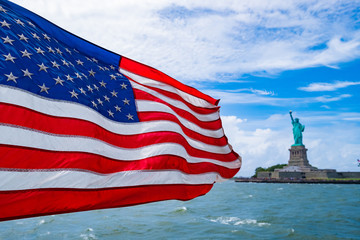 Naklejka premium American flag waving in the wind with The Statue of Liberty background, 