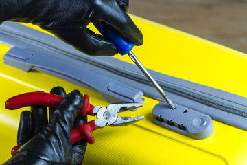 A thief, a fraudster is trying to crack, open a combination lock on a suitcase. Theft concept
