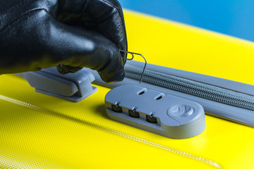 A thief, a fraudster is trying to crack, open a combination lock on a suitcase. Theft concept