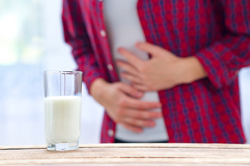A woman feels bad, has an upset stomach, bloating due to lactose intolerance. Dairy intolerant person. Health care concept. Lactose intolerance and dairy products