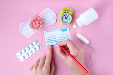 Tampon, feminine, sanitary pads for critical days, feminine calendar, alarm clock, pain pills during menstruation and a pink flower on a pink background. Care of hygiene during menstruation. 