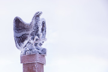 The ski resort is snow-covered with an eagle statue on the top of the mountain and snow-covered sky in the background