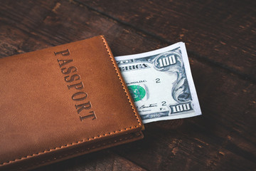Fototapeta premium American hundred dollars and passport on a wooden table. Money concept, financial concept.