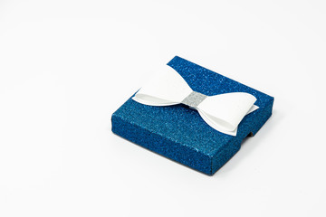 Blue sparkling present box with a white bow on top of it.