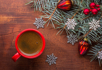 Obraz na płótnie Canvas Red cup of coffee and fir branch with Christmas decorations on old wooden table.