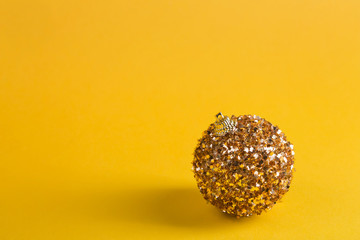 idea of minimal christmas concept, golden christmas ball on yellow background, copy space
