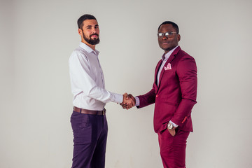 male businessman and his Aro-American partner shaking hands in the studio on a white background
