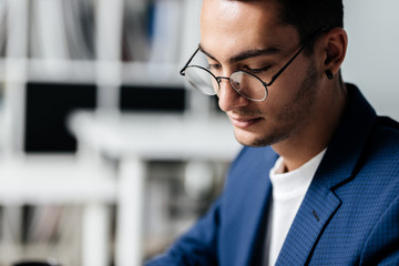 Fototapeta premium Portrait of dark-haired young architect in glasses dressed in blue checkered jacket