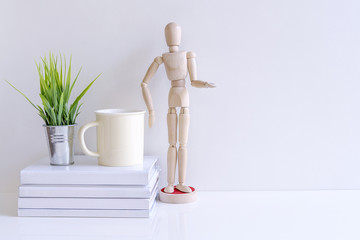 Mockup wooden doll,book,cup and houseplant on white table