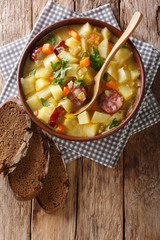 Vegetable thick potato soup with sausages in a bowl close-up. Vertical top view
