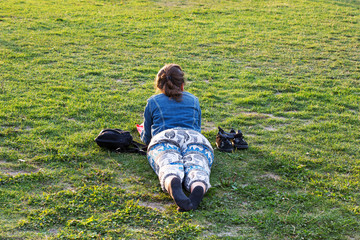 Frau liegt im Gras und liest