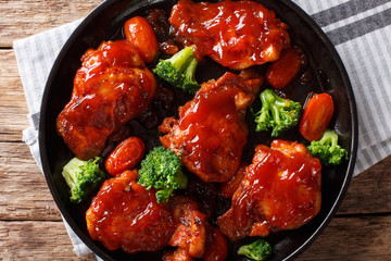 fried chicken thighs with catalina sauce and tomatoes, broccoli close-up on a plate. horizontal top...