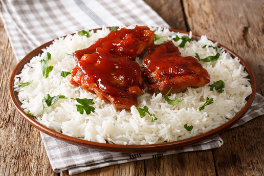 glazed Catalina chicken with spicy sauce and basmati rice close-up on a plate. horizontal