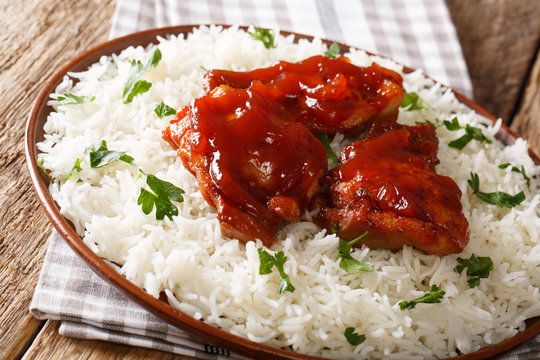 Delicious glazed chicken with spicy sauce and rice close-up on a plate. horizontal
