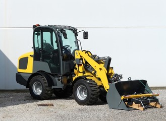 Brand new mini loader, white wall on background