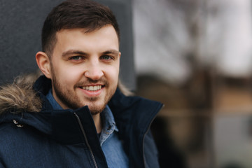 Portrait of handsome young man in winter jacket in front of window