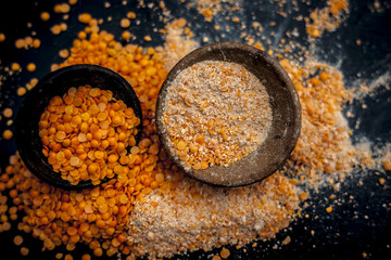 Close up of raw pink lentils in a clay bowl on wooden surface with its powder.
