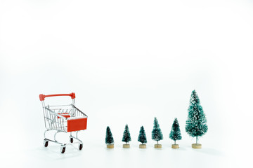 Many different size of christmas trees near a red shopping cart on white background with copy...