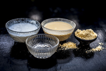 Close up of herbal home remedy for hair fall on wooden surface i.e. gram flour raw well mixed with water and curd in a glass bowl.