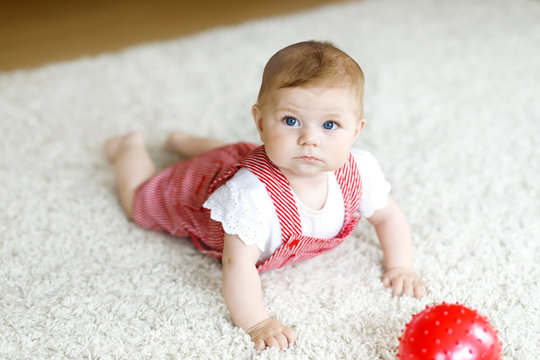 Cute baby girl playing with red gum ball.