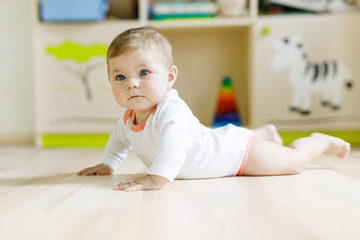 Fototapeta premium Cute baby girl learning crawling and sitting in children room