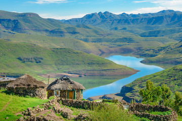 Lesotho traditional hut house homes in Lesotho village in Africa. Beautiful scenic landscape of village in daytime with typical huts built by villagers by the lake of Mohale Dam - obrazy, fototapety, plakaty