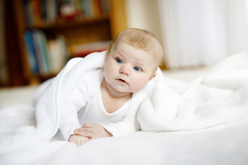 Baby girl wearing white towel or winter overal in white sunny bedroom