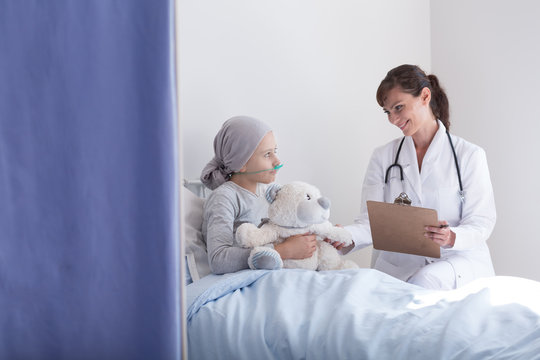 Smiling Doctor With Stethoscope Talking With Kid With Cancer Hugging Plush Toy