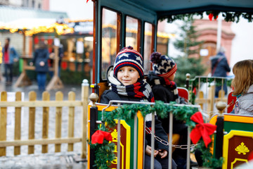 Little kid boy on carousel at Christmas market