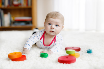 Cute baby girl playing with colorful wooden rattle toy